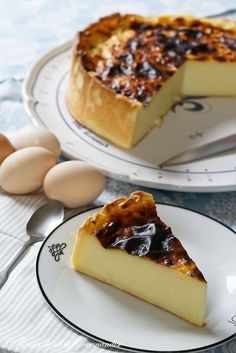 a slice of cheesecake on a plate with an egg next to it and another pie in the background