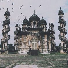 an old building with birds flying over it