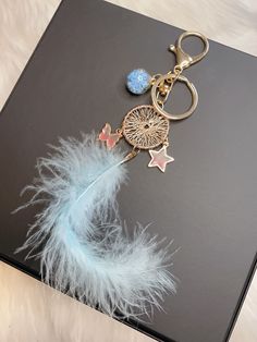 a keychain with a feather and star charms on it