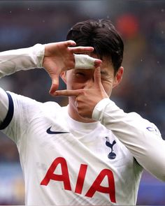 a young man holding his hand up to his face and making the peace sign with his fingers