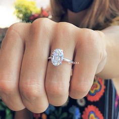 a woman's hand with a diamond ring on her finger, showing the center stone