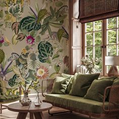 a living room with floral wallpaper and green couches in front of a window