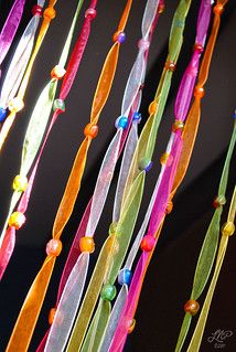 multicolored streamers are hanging from a black wall in front of a window