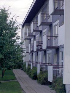 an apartment building with balconies on the second floor and trees in front of it