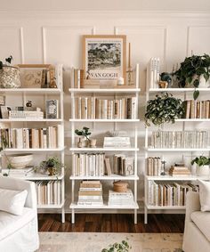 a living room filled with lots of white bookshelves next to a couch and coffee table