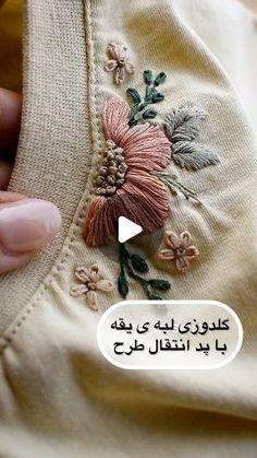 someone is stitching on an embroidered shirt with flowers and leaves in arabic writing,