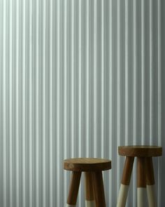 two wooden stools sitting next to each other in front of a wall with vertical blinds