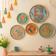 colorful plates are hanging on the wall above a table