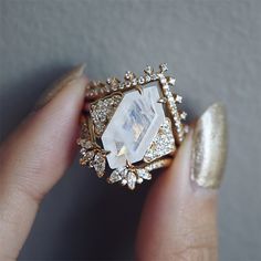 a close up of a person's hand holding a ring with diamonds on it