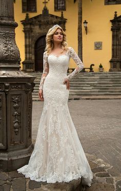 a woman in a white wedding dress standing on a stone walkway next to a yellow building