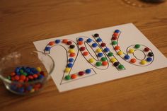 a card with the number twenty two made out of candy and gummy dots next to a bowl of candies