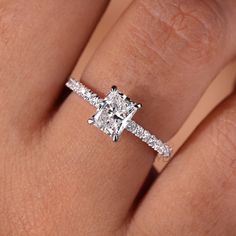 a woman's hand with a diamond ring on her finger, showing the center stone