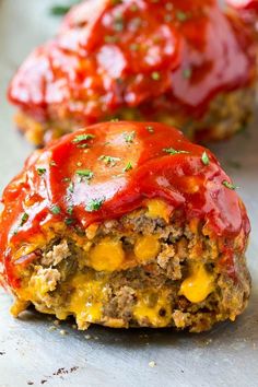 two meatloaf patties with ketchup and cheese on top are sitting side by side