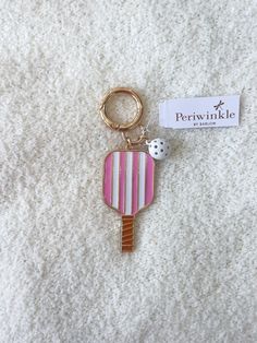 a pink and white striped tennis racquet keychain with a ball on it