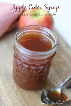 an apple cider syrup in a glass jar on a cutting board with spoons