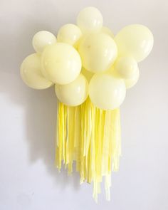 a bunch of white balloons hanging from the ceiling with tassels attached to it