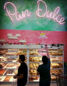 two people standing in front of a bakery counter