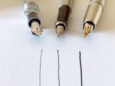 three fountain pens sitting on top of a white paper