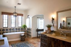 a bath room with a tub a sink and a mirror