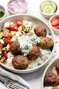 meatballs and rice in a bowl on a table with other food items around it