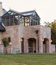 a large stone house with lots of windows on the front and side of it's roof