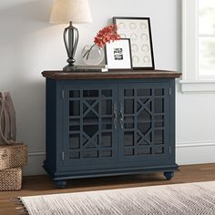 a blue cabinet sitting on top of a wooden floor next to a lamp and pictures