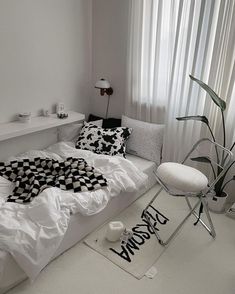 a white bed sitting in a bedroom next to a window covered in black and white sheets