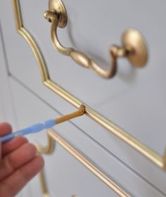 someone is painting the handles on a gold dresser