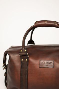 a brown leather duffel bag sitting on top of a white table