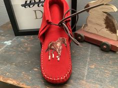 These handmade moccasins will not disappoint. This pair is a red suede leather emblazoned with dancing ponies. Made completely of leather, by hand, by me.  This pair was thought up by a client, which is something I encourage.  Design a pair that makes you and your feet happy! Calf Leather Slip-on Moccasins With Stitched Sole, Handmade Artisan Closed-toe Moccasins, Leather Tassel Slip-on Moccasins, Suede Tassel Slip-on Moccasins, Luxury Red Slip-on Moccasins, Handmade Moccasins, American Leather, Red Suede, May 11