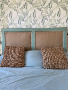 a bed with two pillows on it in front of a wallpapered headboard