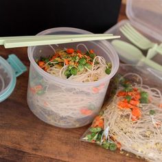 a plastic container filled with noodles and veggies on top of a wooden table