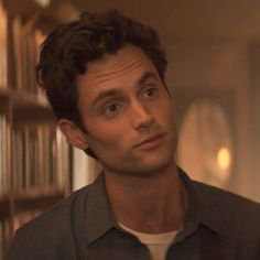 a man standing in front of a bookshelf looking at the camera with an intense look on his face