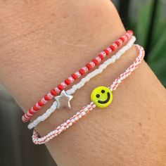 seed bead bracelet with a yellow smiley face bead. black stripes, red stripes and pink strung on elastic please gently roll on and off to prolong its life handmade in venice, ca Fun Red Jewelry For Friendship, Everyday Red Friendship Bracelets With Colorful Beads, Cute Red Stretch Bracelet For Friendship, Cute Red Friendship Stretch Bracelet, Cute Red Beaded Friendship Bracelets, Everyday Red Friendship Bracelet With Round Beads, Playful Red Beaded Bracelets, Cute Red Friendship Bracelets, Cute Red Friendship Bracelets With Round Beads