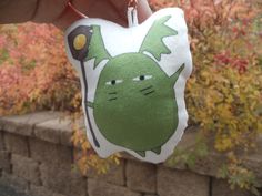 a hand holding a green and white keychain with a cartoon character on it