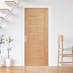 a wooden door sitting next to a white chair in a living room under a stair case