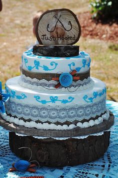 a three tiered cake sitting on top of a blue doily covered tablecloth