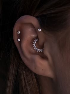 a close up of a person's ear with three piercings