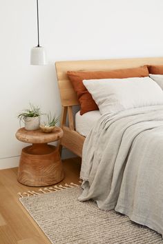 a bedroom with a bed, nightstand and plant on the side table next to it