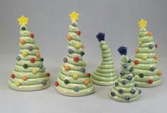 three small ceramic christmas trees in different colors and sizes, with stars on the top