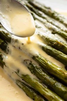 asparagus being drizzled with white sauce