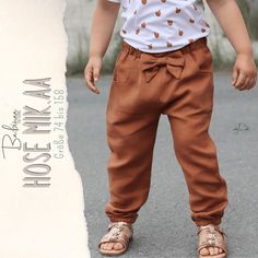 a small child standing in the street wearing brown pants