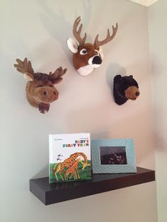 three stuffed animals are mounted on the wall above a bookshelf in a children's room