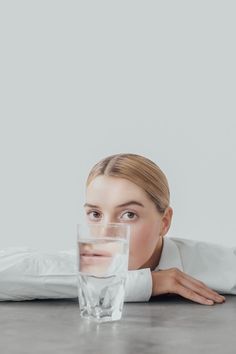 a woman laying on the floor with a glass of water in front of her face