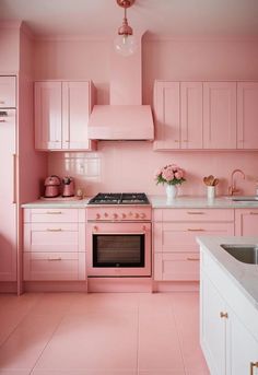 a kitchen with pink cabinets and white counter tops, an oven and sink are in the center