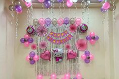 balloons and streamers are hanging from the ceiling in front of a hello kitty theme