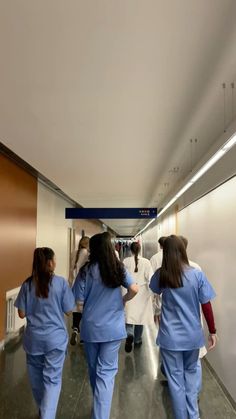 three women in scrubs are walking down the hallway with their backs to each other