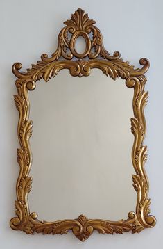 an ornate gold framed mirror hanging on the wall