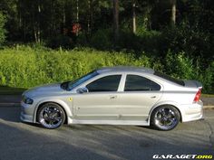 a silver car is parked on the side of the road in front of some bushes