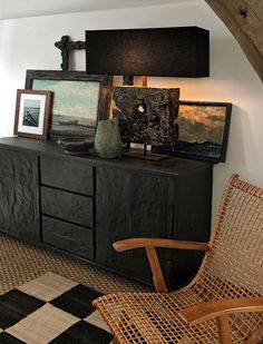 a room with a black cabinet and some pictures on the wall next to a chair